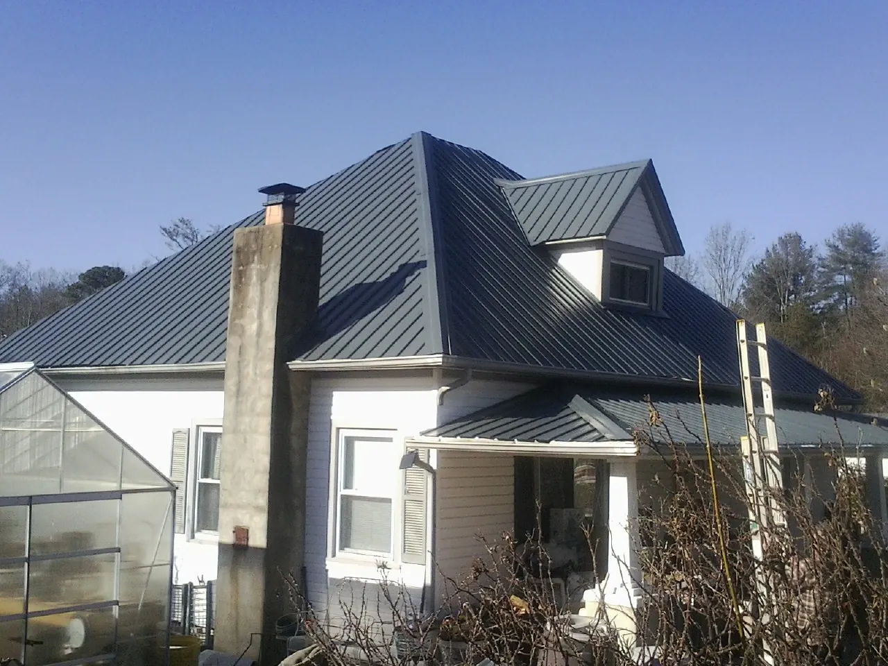 Dark blue standing seam metal roof on a white farmhouse with dormer — Slate & Tile Roof Repair by Roofing Brothers in Days Creek