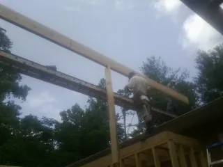 Carpenter setting a ridge beam over a new addition frame — Ice Dam Removal by Roofing Brothers in Days Creek