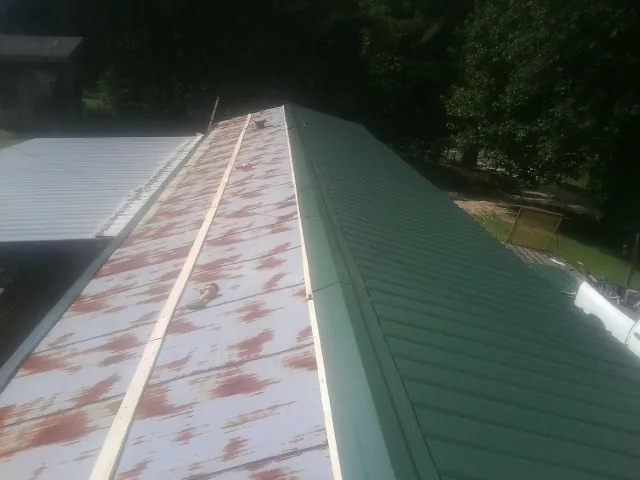Old rusted panels beside newly installed green metal roofing — Wind Damage Roof Repair by Roofing Brothers in Days Creek