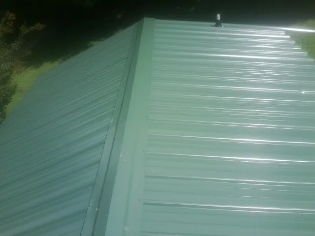 New green metal panels meeting at the ridge of a roof — Flat Roof Repair work by our crew in Days Creek