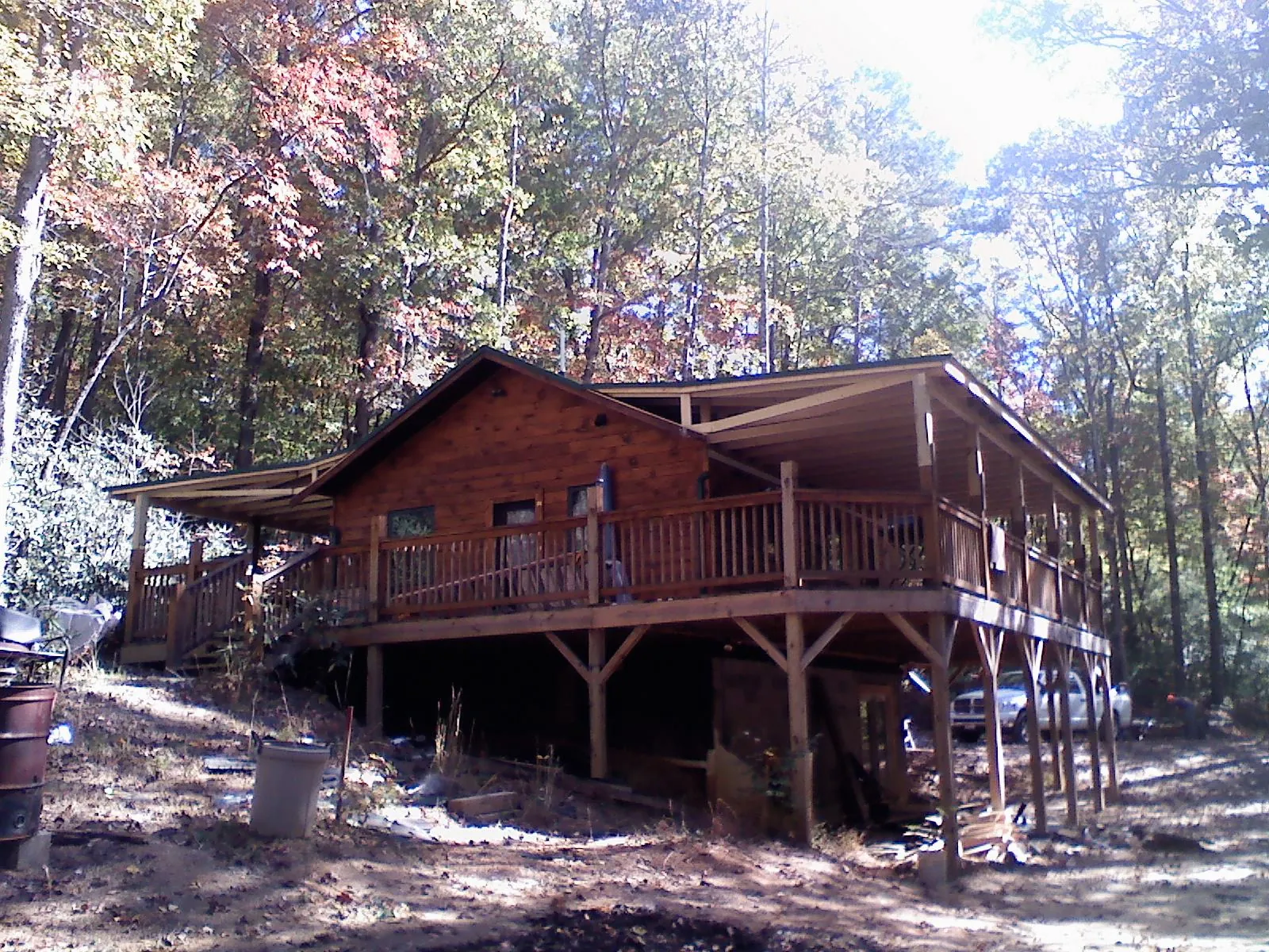 Log cabin with a wraparound porch and metal roof in the fall in Days Creek