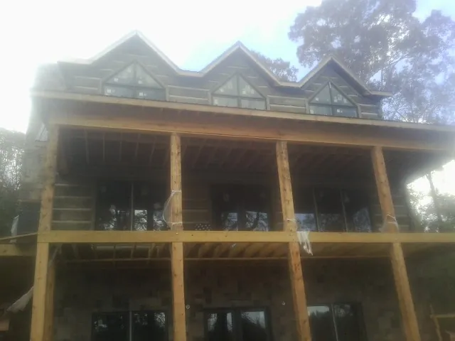 Dormers and porch framing on a large log home under construction — Roof Coating work by our crew in Days Creek