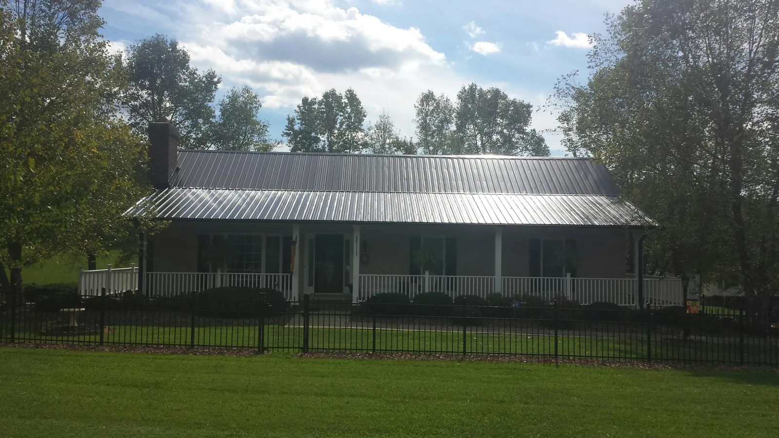 Gray metal roof on a brick ranch with a full width front porch — Gutter Guard Installation work by our crew in Days Creek