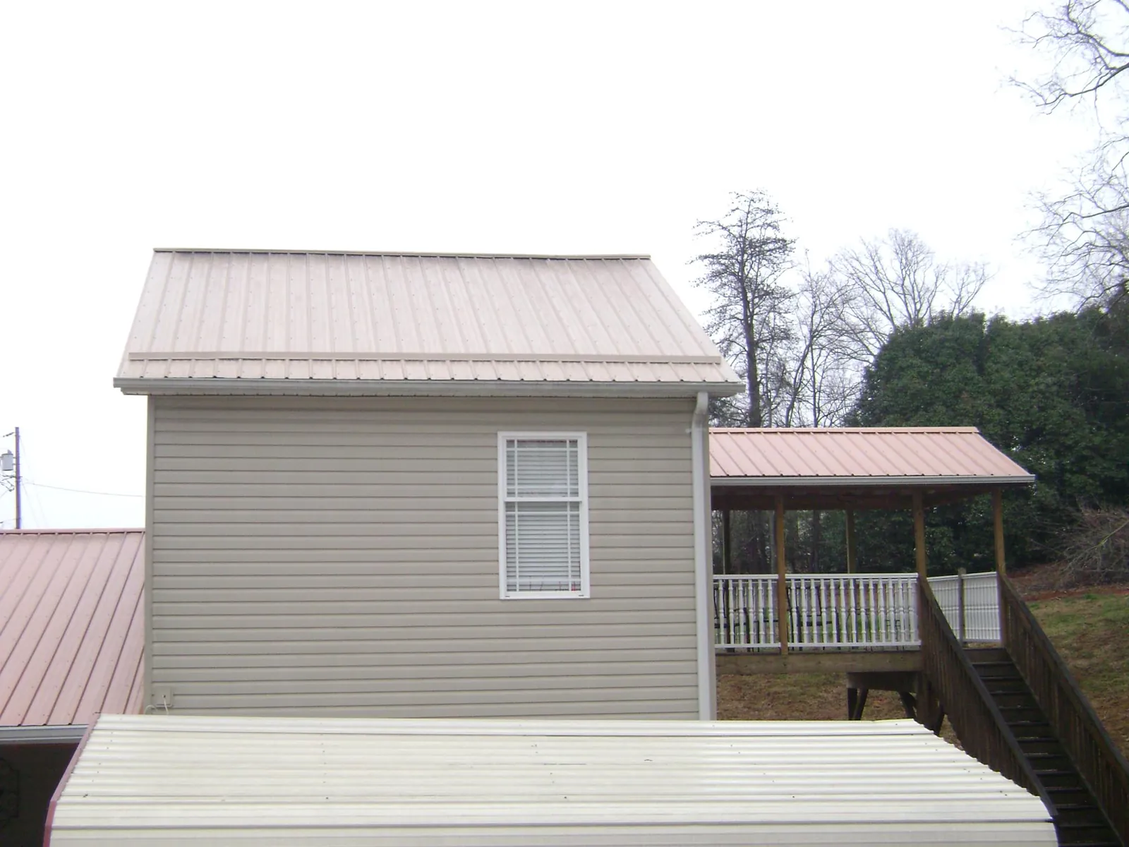 Tan metal roofs on a two story addition and attached porch, from a Roof Replacement job in Days Creek
