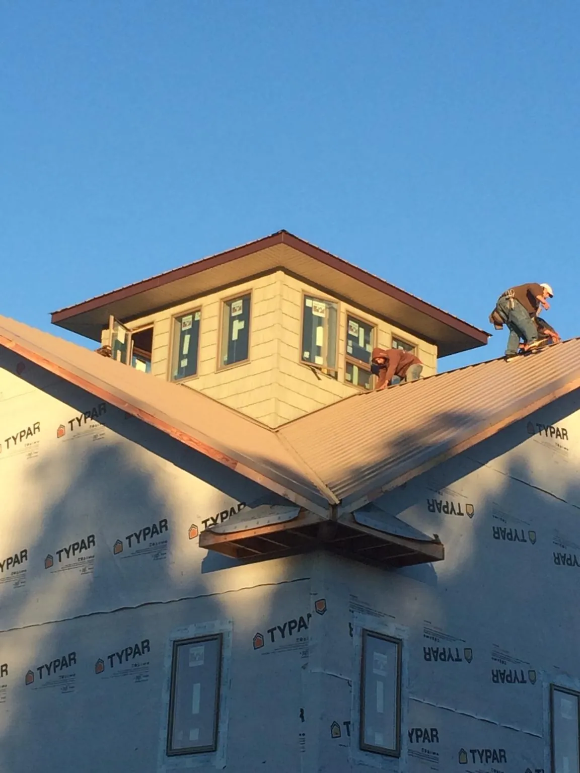Roofers working around a rooftop cupola on a new metal roof at sunset — Roof Waterproofing in Days Creek by Roofing Brothers
